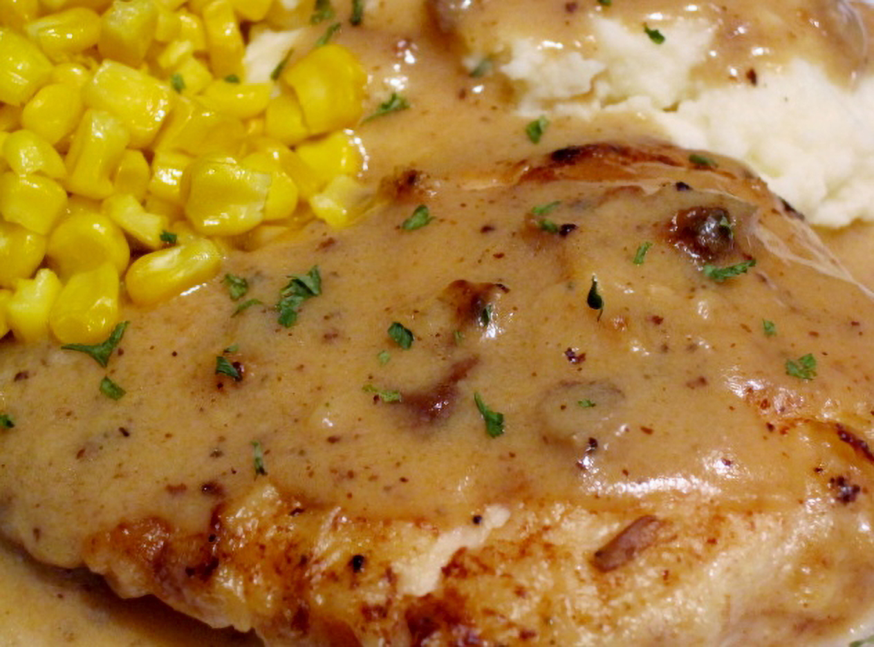 Baked Buttermilk Chicken plated with mashed potatoes and corn and smothered in gravy